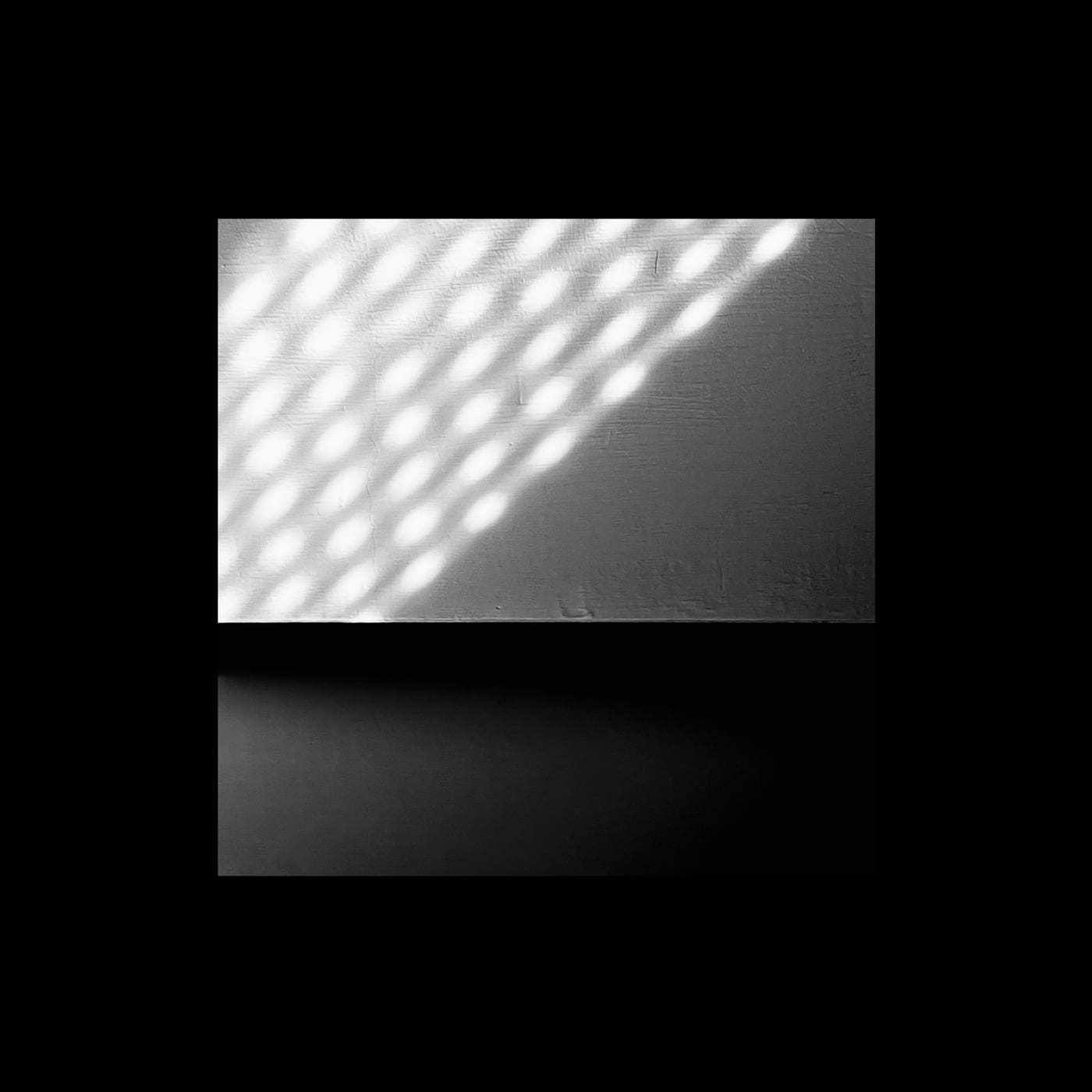A grid of soft light dots falling diagonally across a wall.