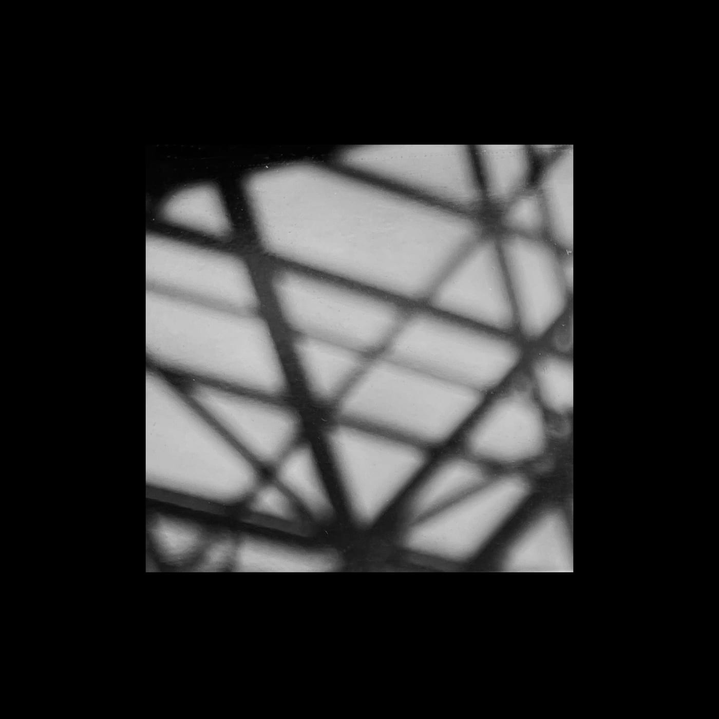 Crossing bars of a glass roof against a blown-out sky.
