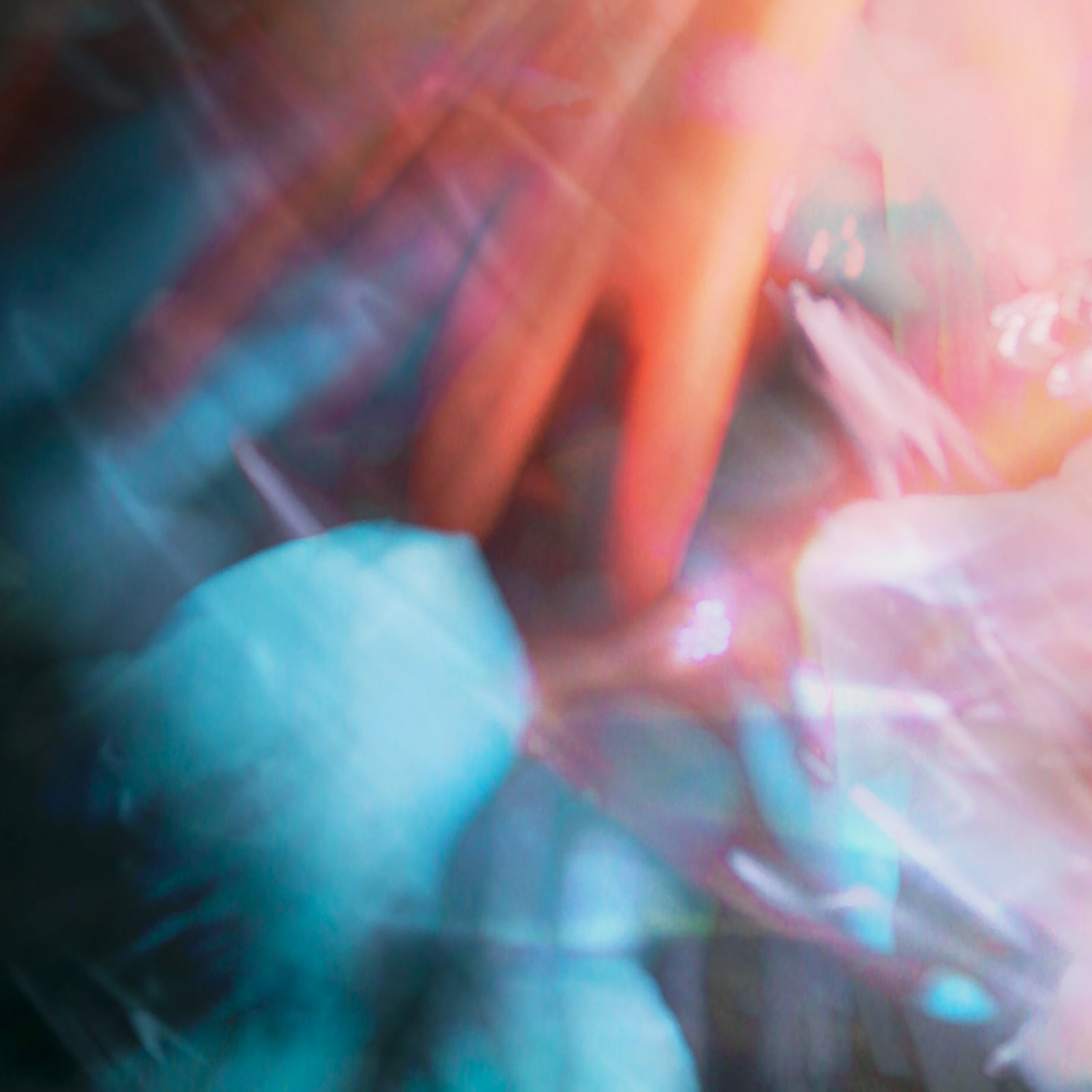 Hands caught in cyan and coral light.